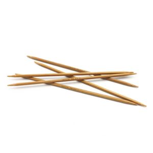 Five 6 inch bamboo double point needles scattered on a white background